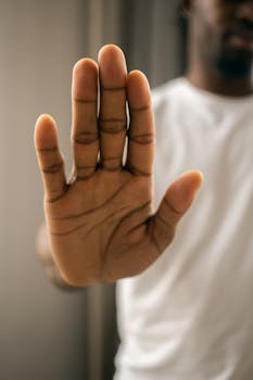 Close-up of an African American man gesturing stop with his hand, unrecognizable, indoors.